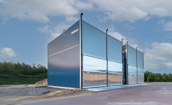 Valutec-Kammertrockner mit blauer Metallfassade und großen Toren auf einem Sägewerksgelände.