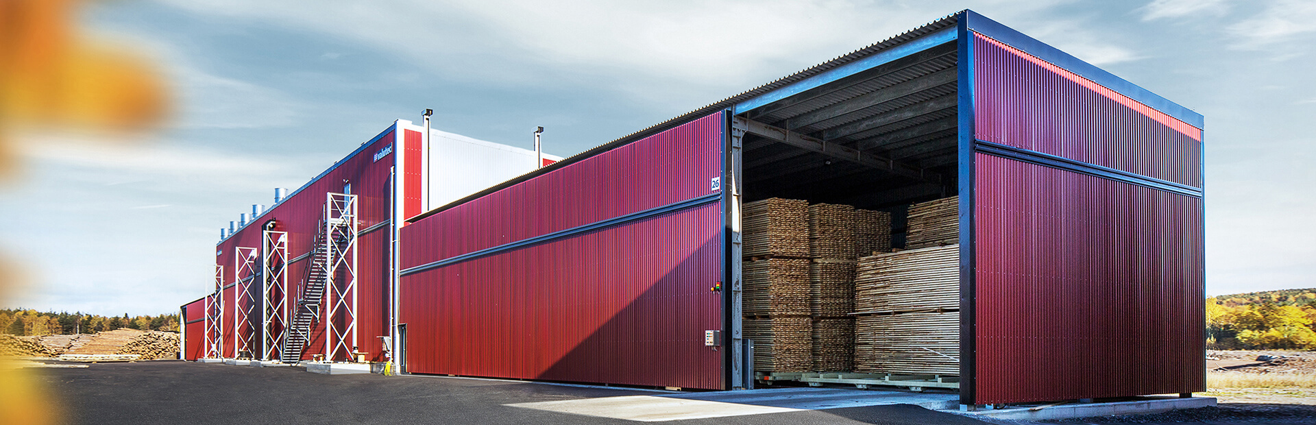 TC-kanaltork från Valutec i röd fasad, lastad med virke på vagnar redo för torkprocess.