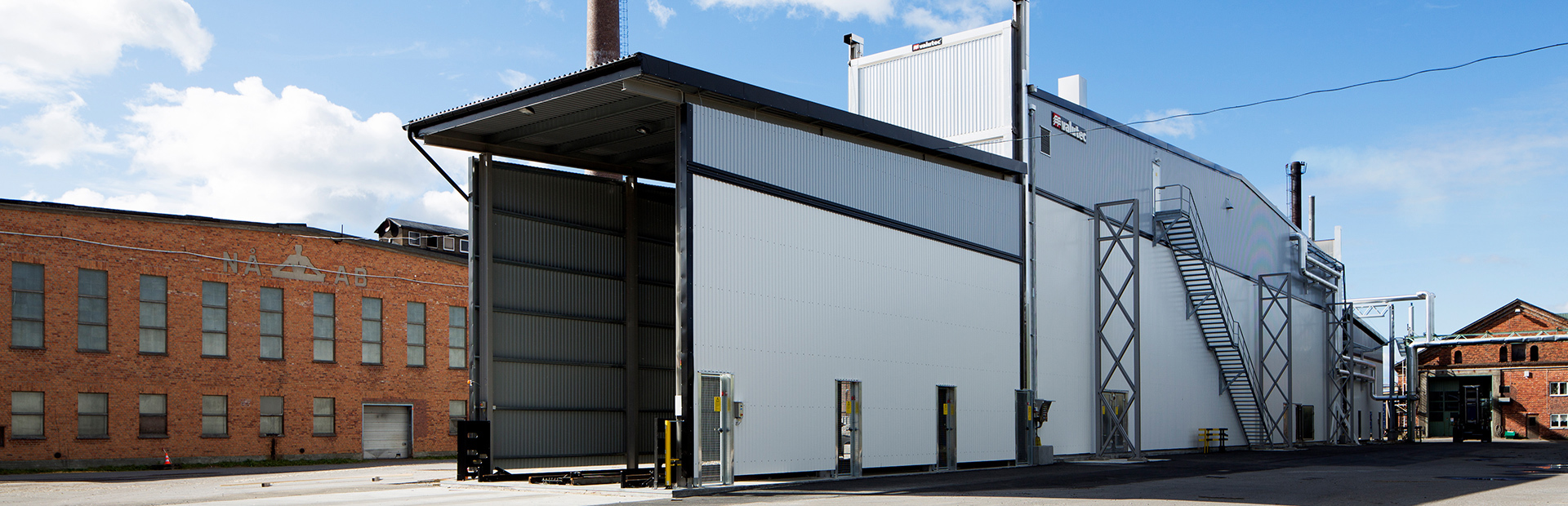 Vit Valutec kanaltork FB med öppna portar, framför ett rött tegelhus