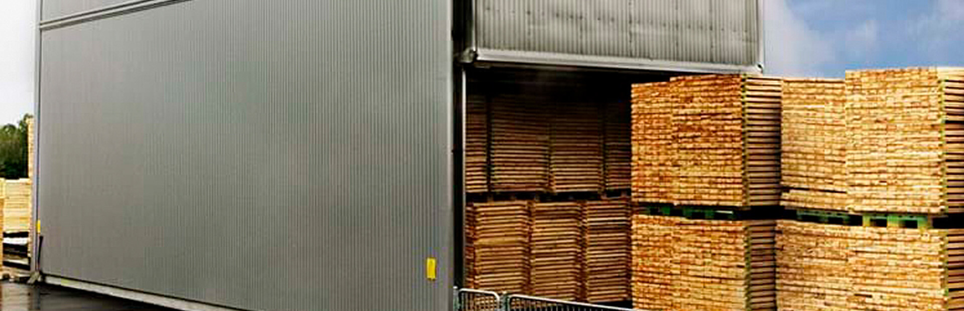 Truckmatad kammartork med staplade virkespaket vid inlastning.